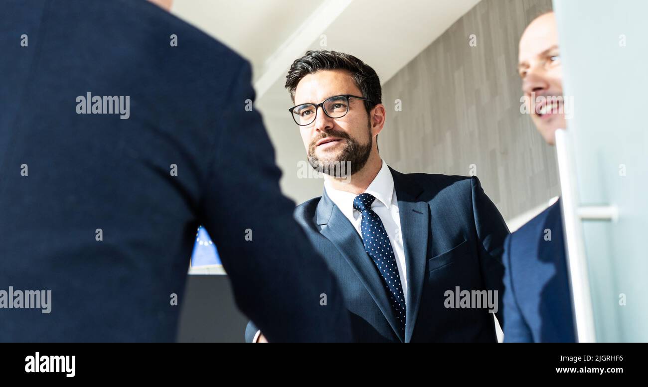 Un grupo de personas de negocios confiadas saludan con un apretón de manos en una reunión de negocios en una oficina moderna o cerrando el acuerdo de trato agitando las manos. Foto de stock