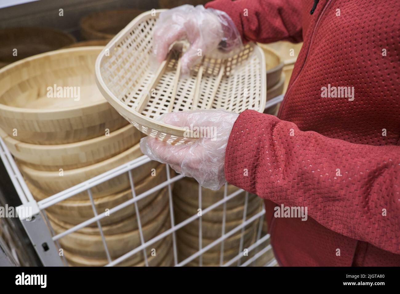 Chica en guantes contra el virus compra platos de mimbre con pinzas de madera en la tienda Foto de stock