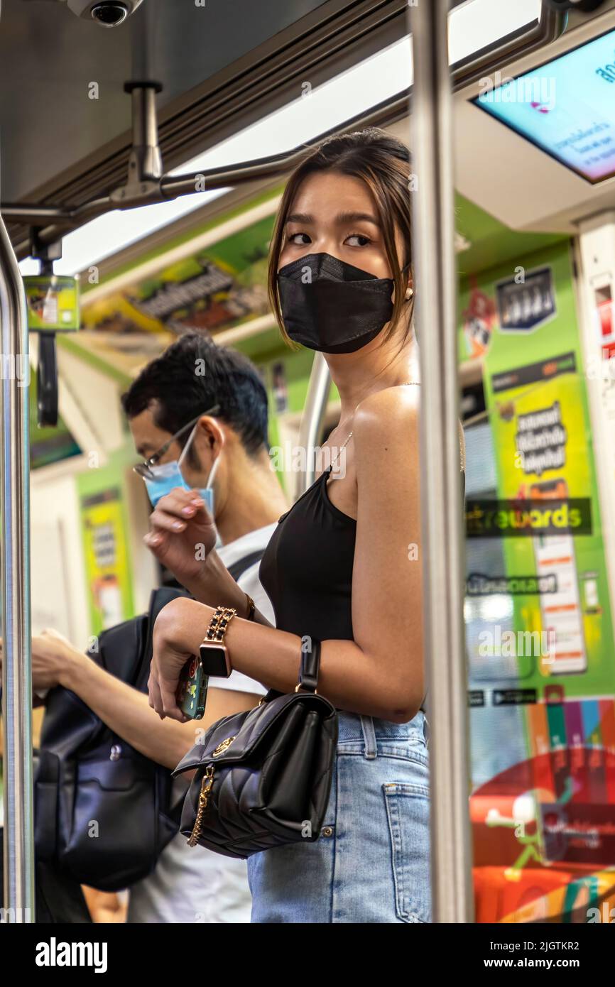 Pasajeros con máscaras faciales en el tren aéreo BTS tailandés, Bangkok, Tailandia Foto de stock