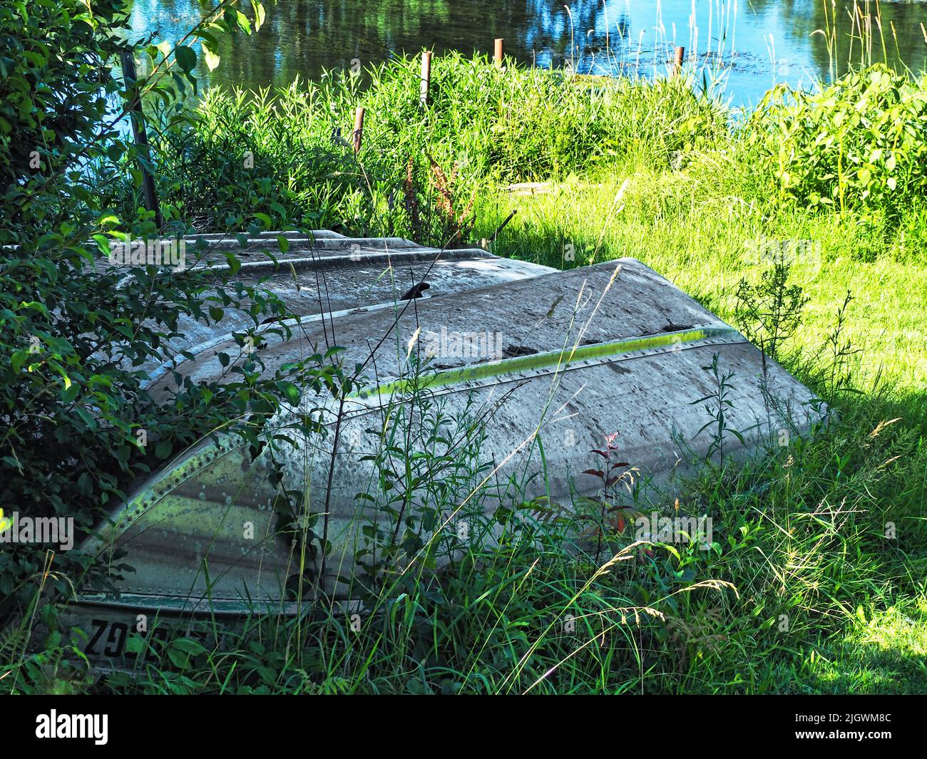 Tres botes a remo almacenados en una orilla del lago Foto de stock