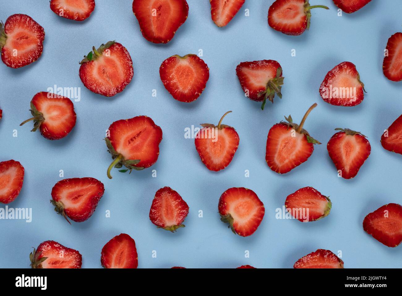 Fresa giratoria cortada por la mitad sobre un fondo azul, textura de fresa o un fondo moderno de frutas de verano. Metraje 4K de alta calidad Foto de stock