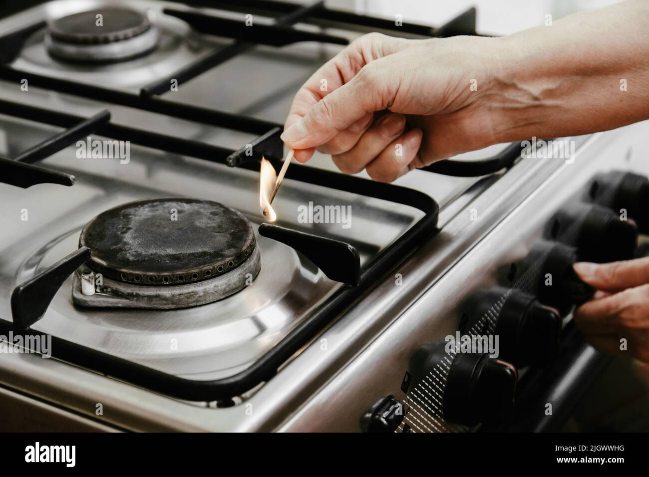 La mano de una mujer adulta con una cerilla enciende una hornilla de gas o  una estufa de gas en su apartamento Fotografía de stock - Alamy