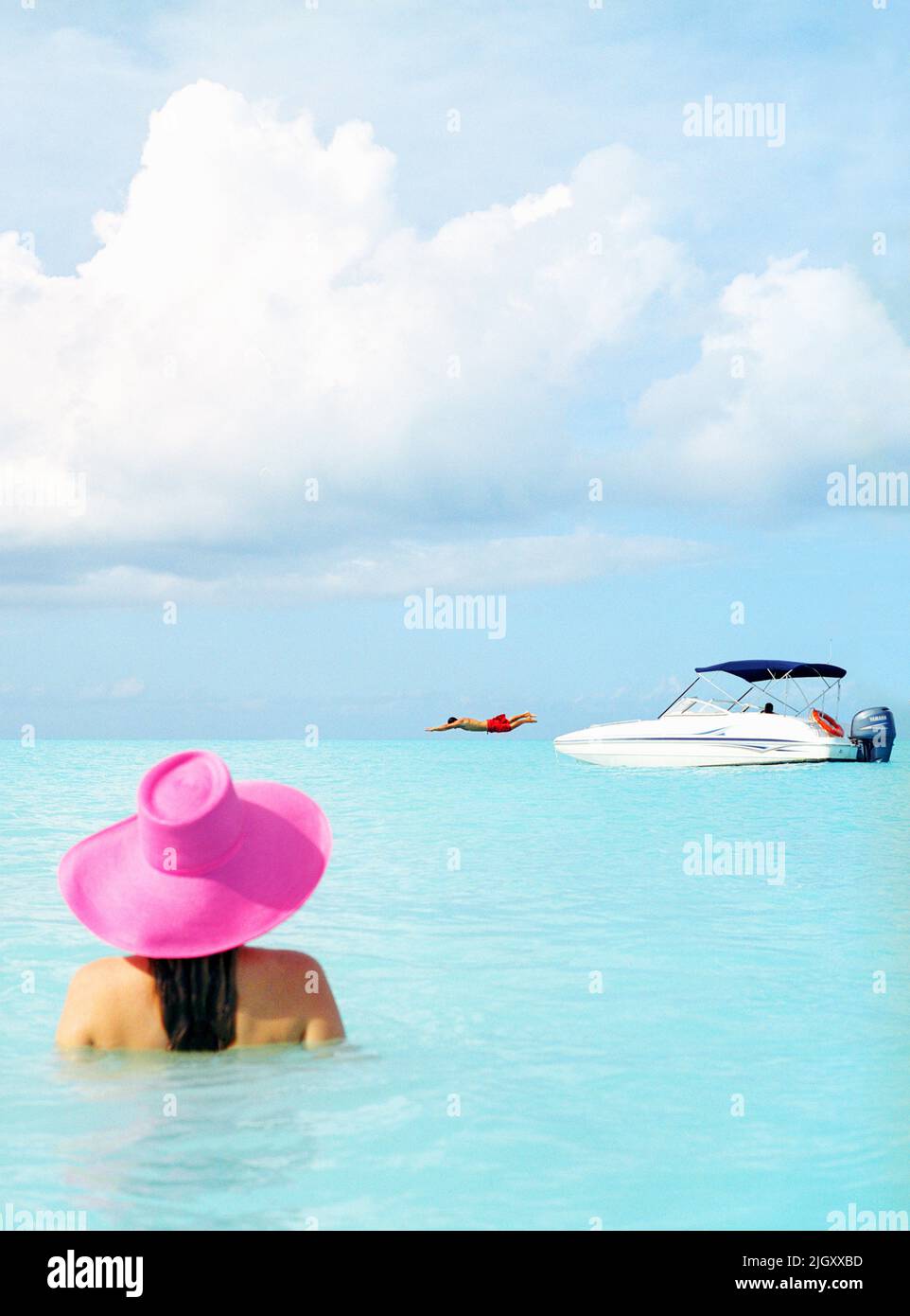 Mujer en el mar con barco en la distancia, Parrot Cay, Turcas y Caicos Foto de stock