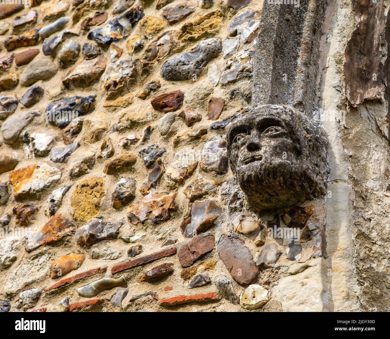 Primer plano de una cara esculpida en el exterior de la iglesia parroquial de Thaxted en la ciudad de Thaxted en Essex, Reino Unido. Foto de stock