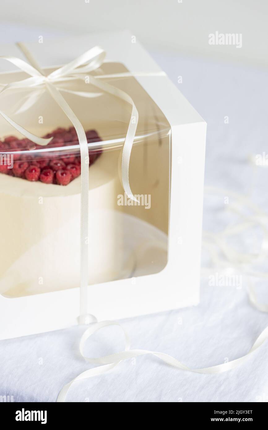 Caja de embalaje para tartas con pastel blanco sobre la mesa. Foto de stock
