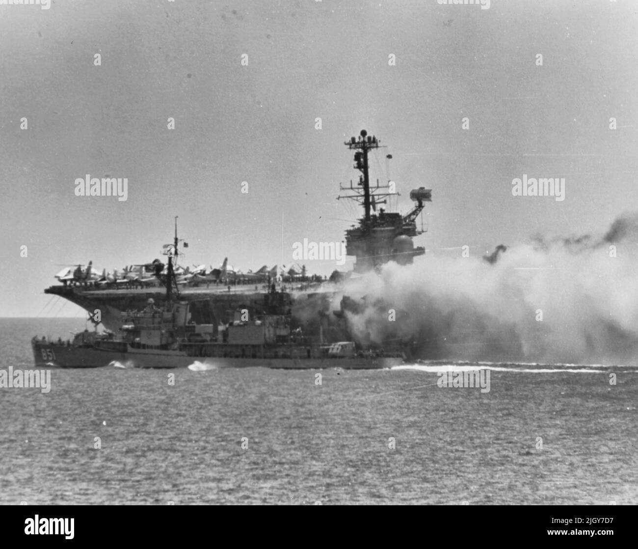 El destructor de la Marina de los EE.UU. USS Rupertus (DD-851) está de pie para ayudar al portaaviones USS Forrestal (CVA-59) a luchar contra los incendios y explosiones de cubierta mientras opera en el Golfo de Tonkin, el 29 de julio de 1967. El capitán del Rupertus maneouvered su nave dentro de 6 metros del portador ardiente, en lo que el Contralmirante Harvey P. Lanham, Comandante de la División 2 del Portador, llamó un acto de 'marinería significativa'. Foto de stock