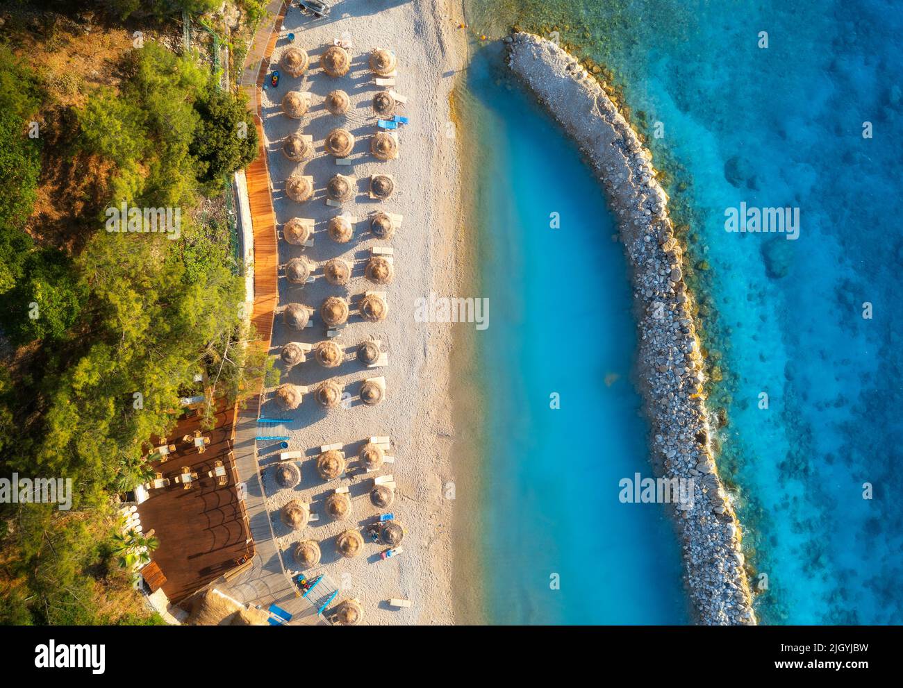 Vista aérea de playa de arena con sombrillas, mar, árboles verdes Foto de stock