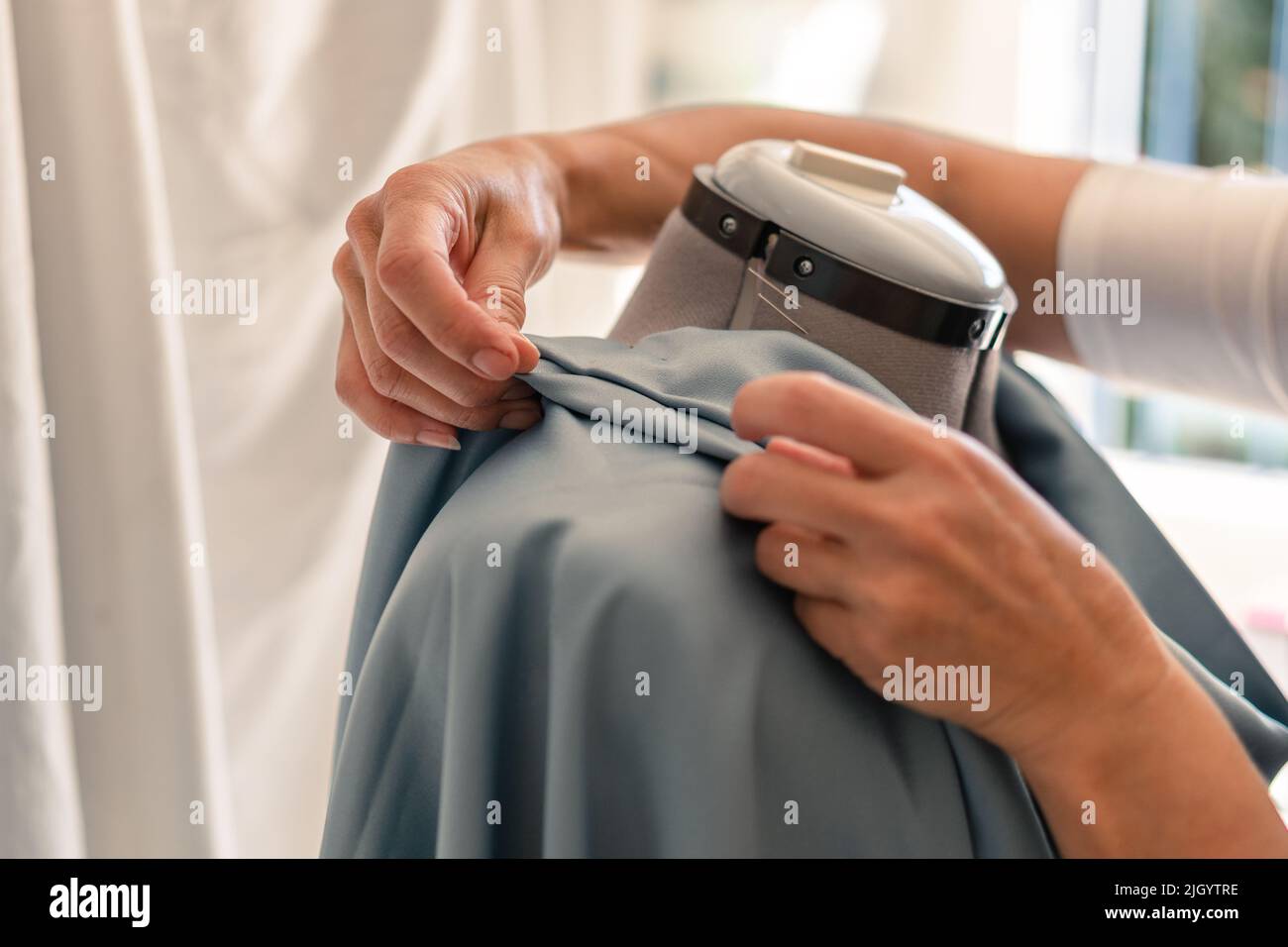 manos de costureras creando pliegues en una prenda sobre un maniquí Foto de stock