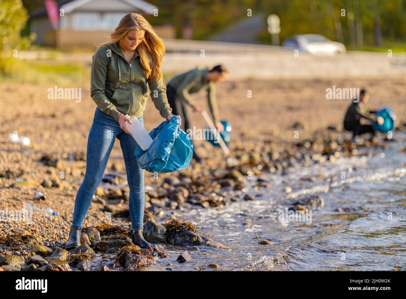 Voluntarios jóvenes dedicados a la limpieza de la playa en el día soleado Foto de stock