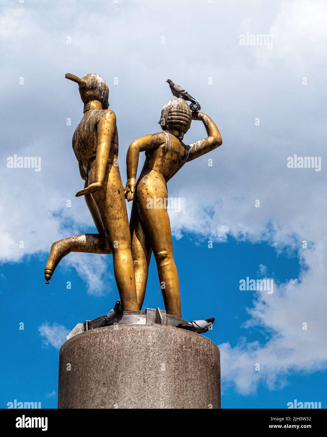 Escultura de bronce “Pareja bailando” del escultor Joachim Schmettau en medio de Hermannplatz, Neukölln, Berlín, Alemania. Lugar de descanso favorito para el pigeo Foto de stock