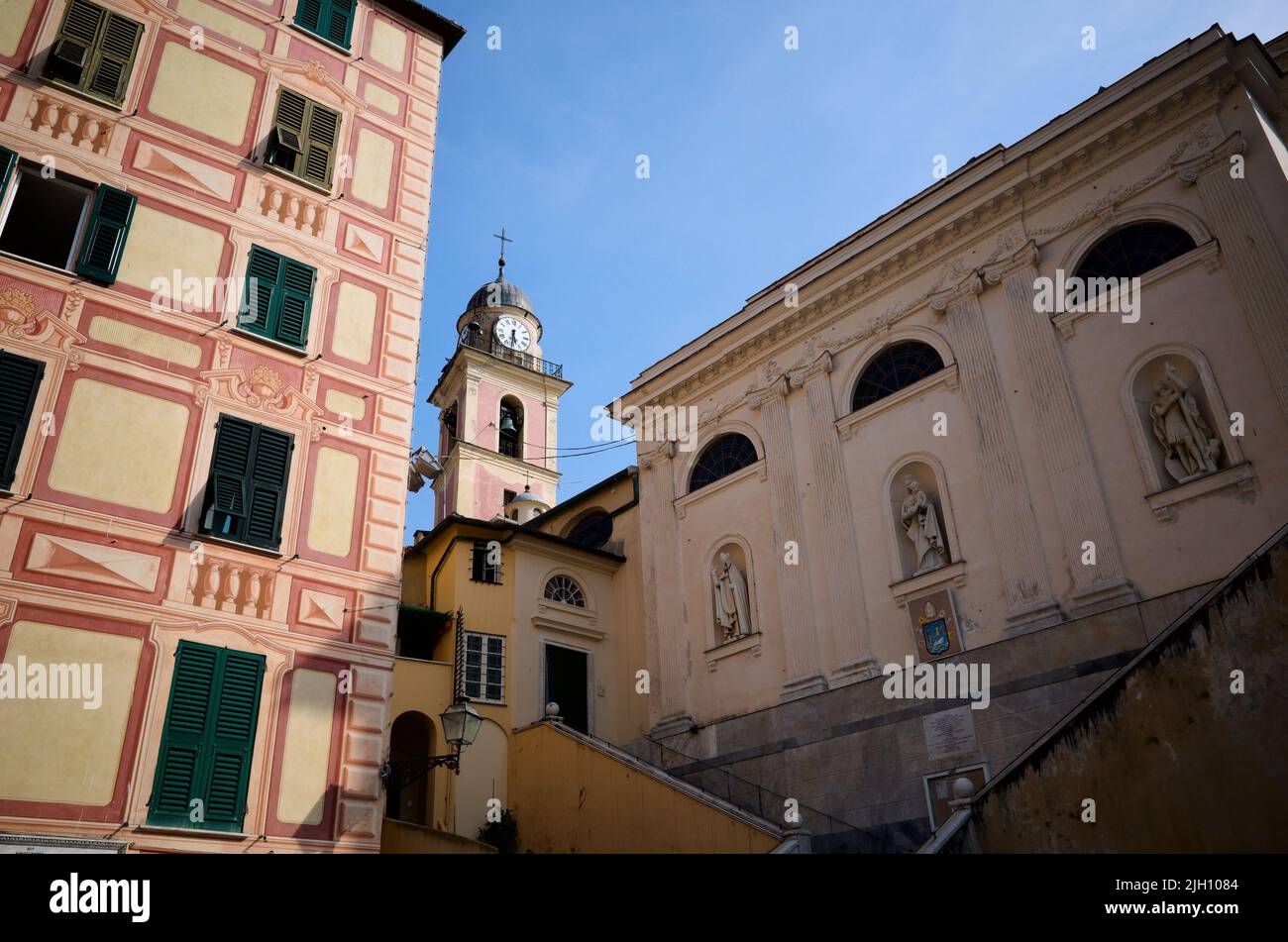 Vista del campanario de la iglesia llamada Basilica di Santa Maria Assunta y la pared lateral del templo con estatuas, Camogli, Liguria, Italia Foto de stock