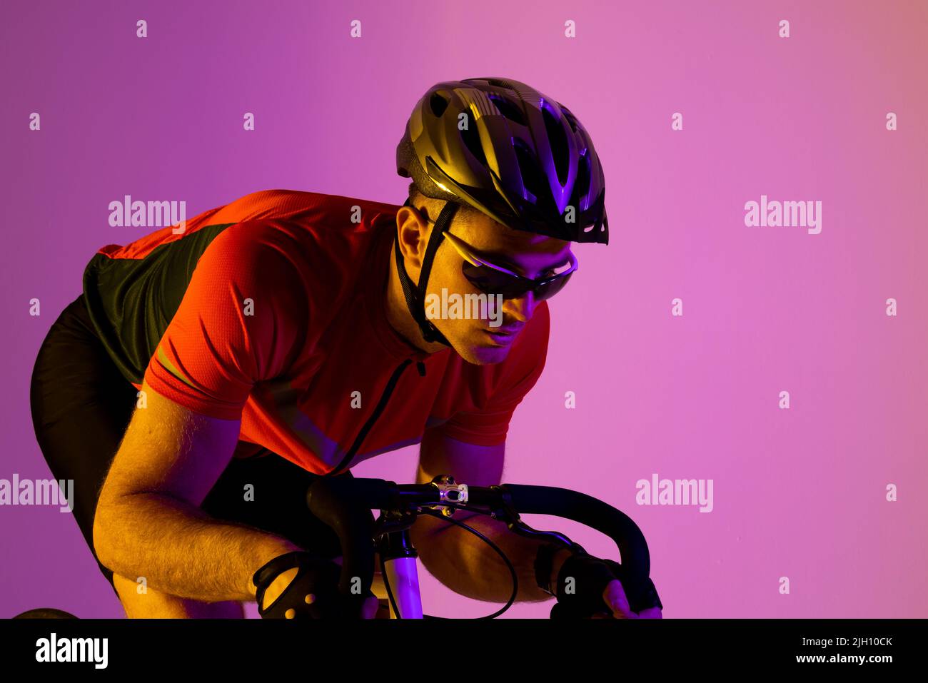 Ciclista caucásico con bicicleta sobre iluminación rosa Foto de stock
