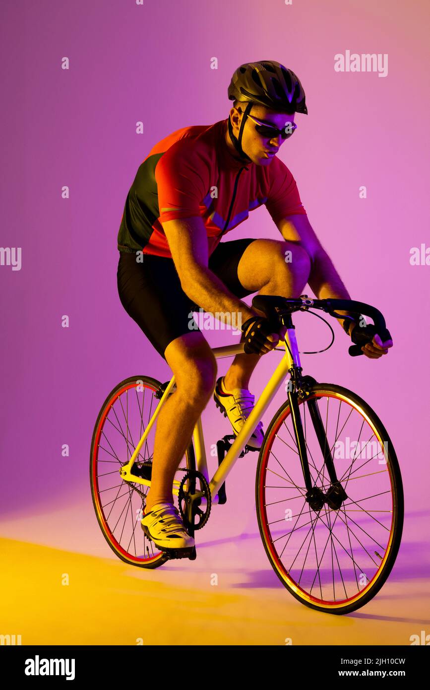Ciclista caucásico con bicicleta sobre iluminación rosa Foto de stock