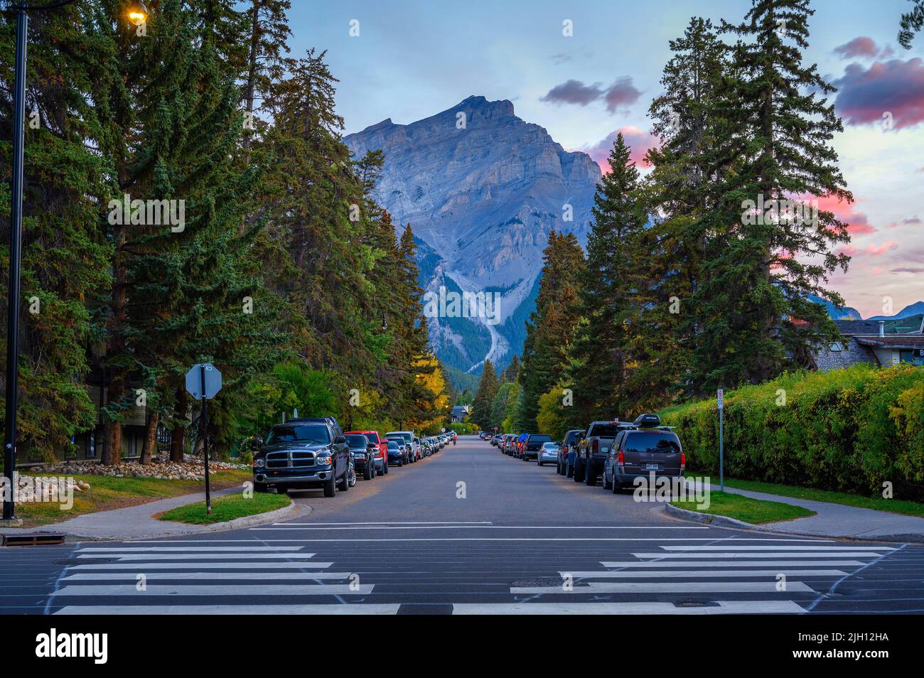 Vista panorámica de la calle de Banff, Canadá, con coches y Cascade Mountain al amanecer Foto de stock