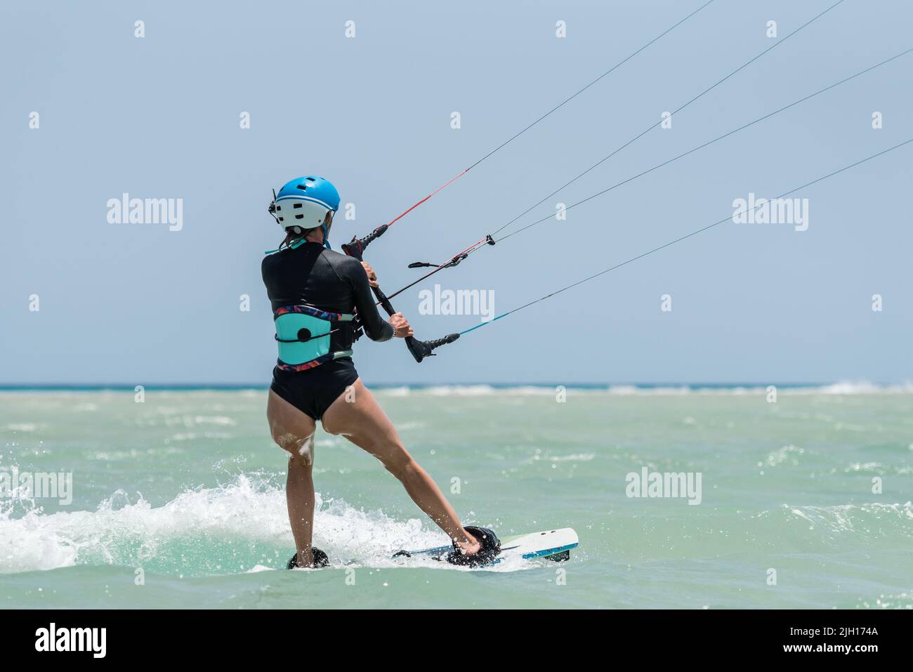 Mujer aprendiendo kitesurf, chica en la escuela de kitesurf. Clases de kite surf en las Islas Canarias, Fuerteventura. El agua comienza en el kite-board. Foto de stock