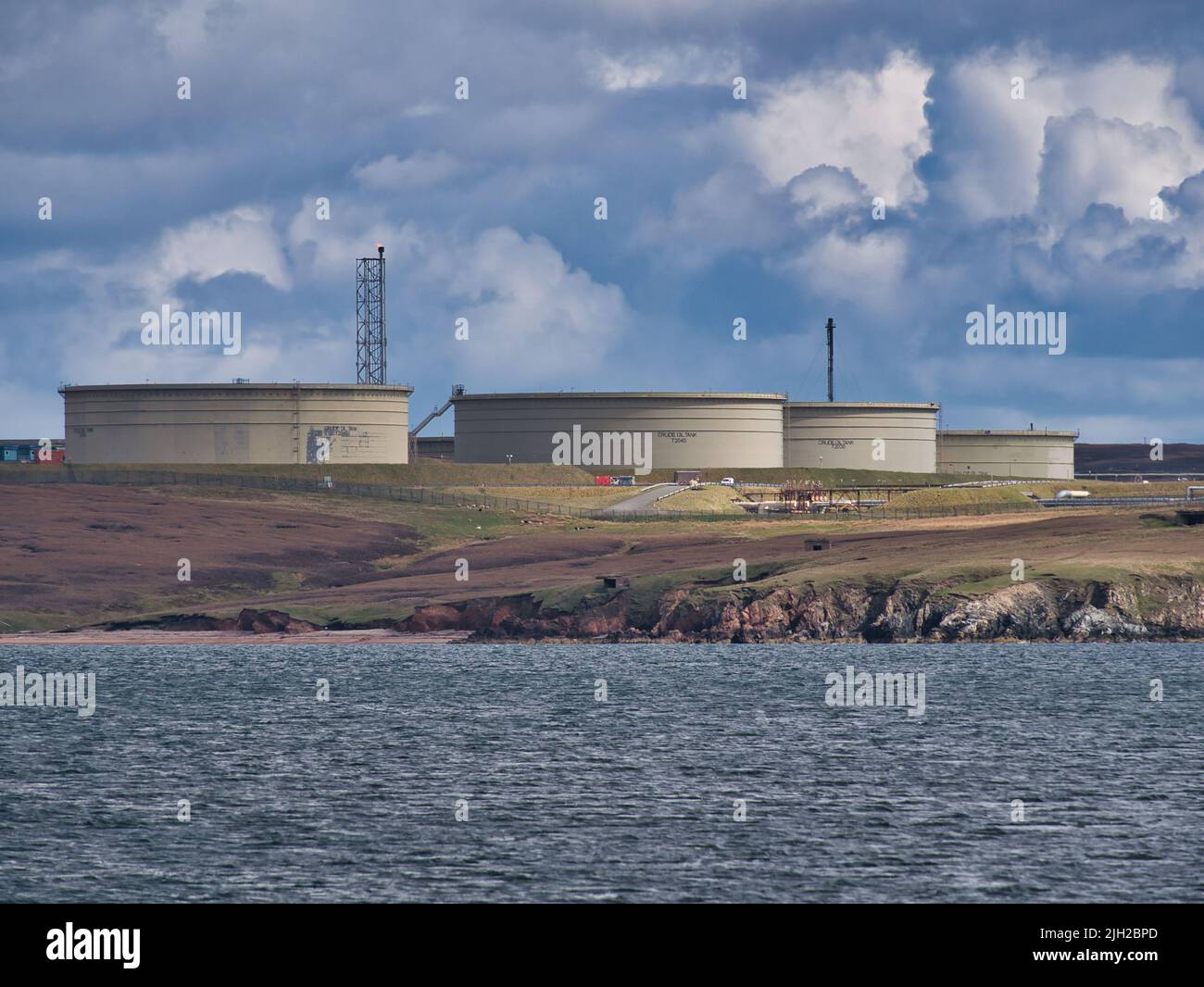 Tanques de almacenamiento de petróleo crudo de hormigón en la terminal de Sullom Voe en Shetland. Tomado bajo el sol en un día nublado. Foto de stock