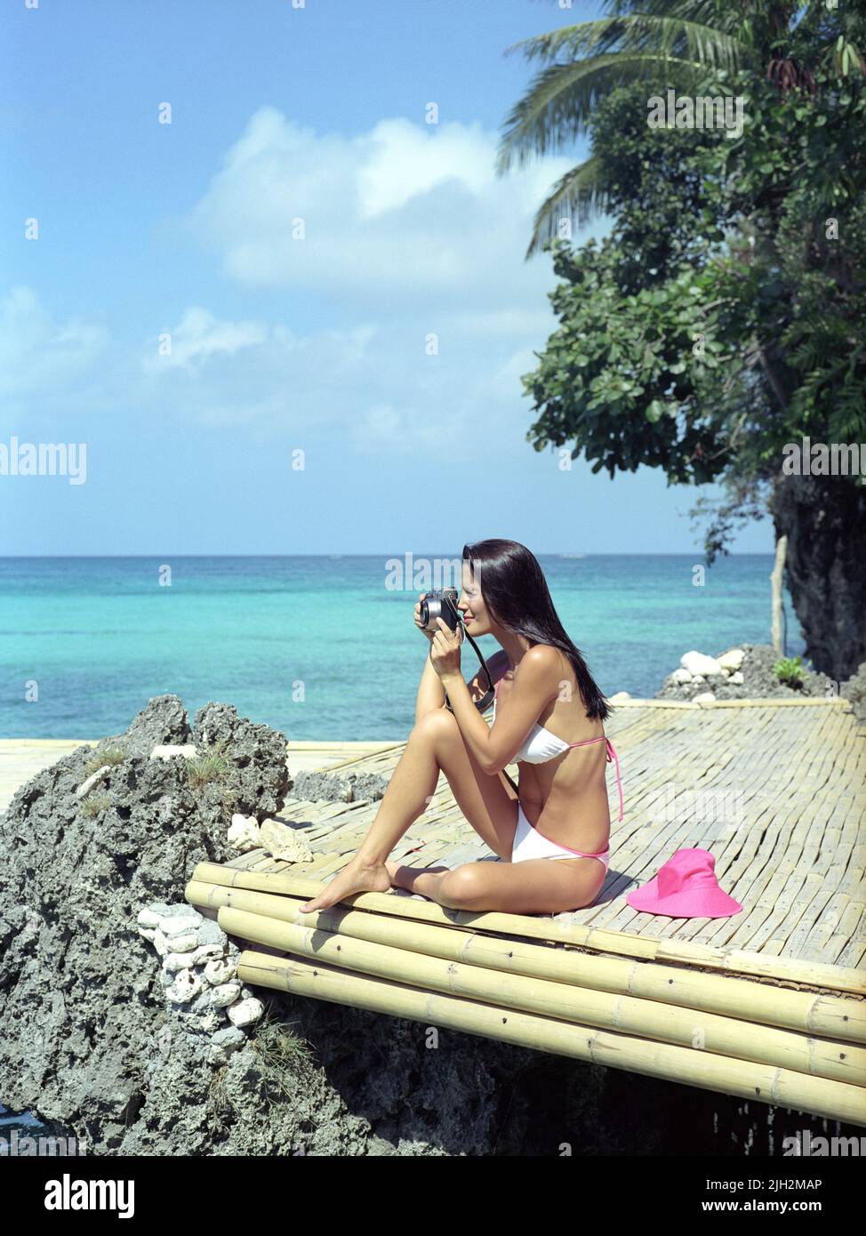 Mujer en bikini tomando una fotografía en un muelle de bambú. Boracay, Filipinas. Foto de stock