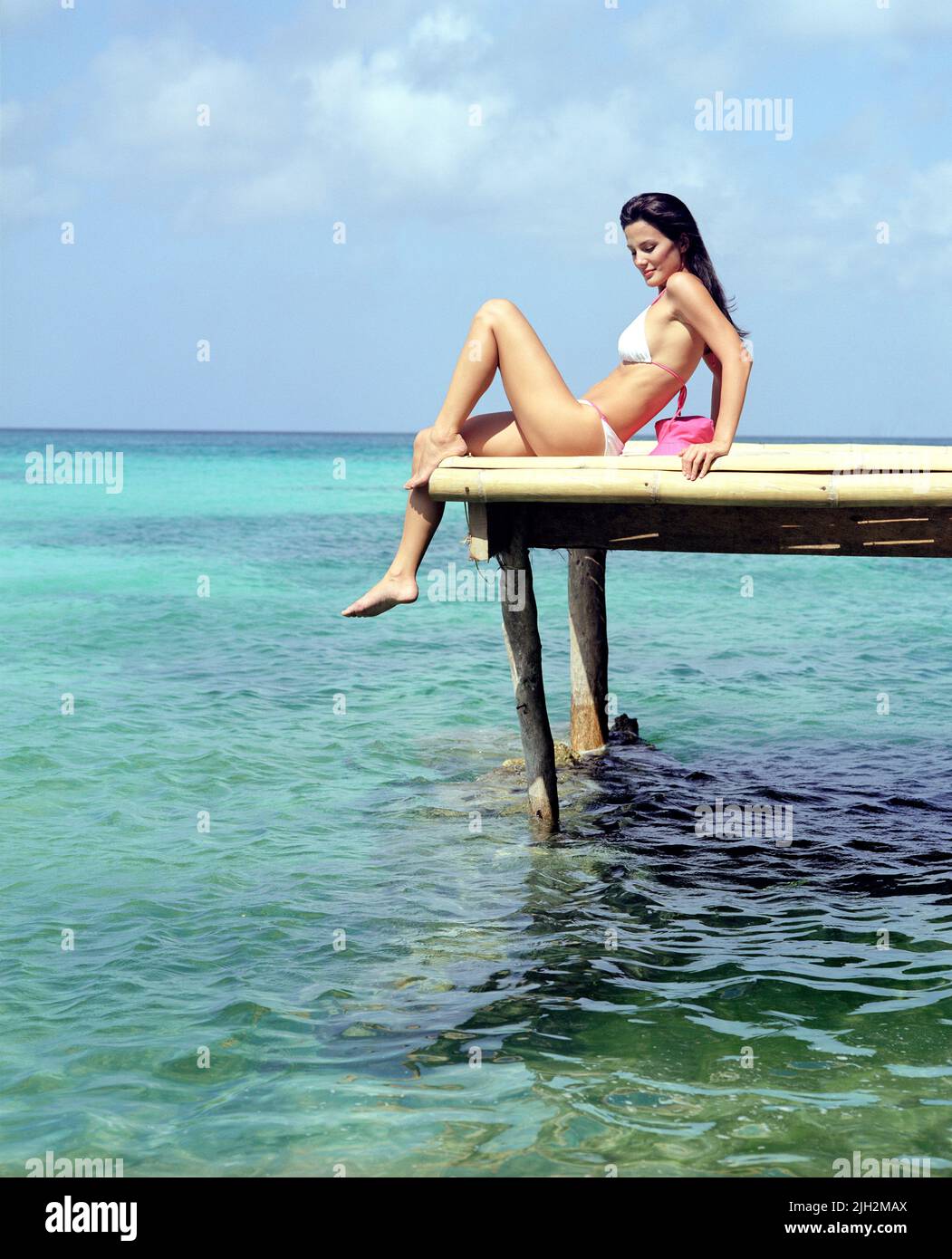Mujer en bikini sentada en el muelle de bambú sobre el agua del mar. Boracay, Filipinas. Foto de stock