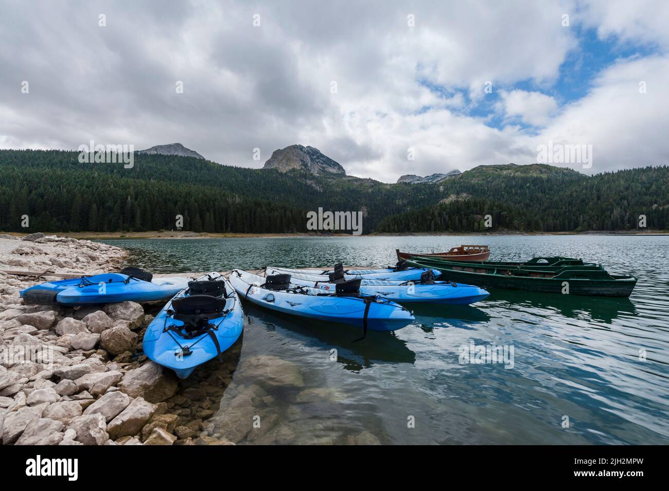 Algunas canoas azules esperando a los turistas en el borde del Lago Negro en el Parque Nacional Durmitor, Municipio de Žabljak, al norte de Montenegro Foto de stock
