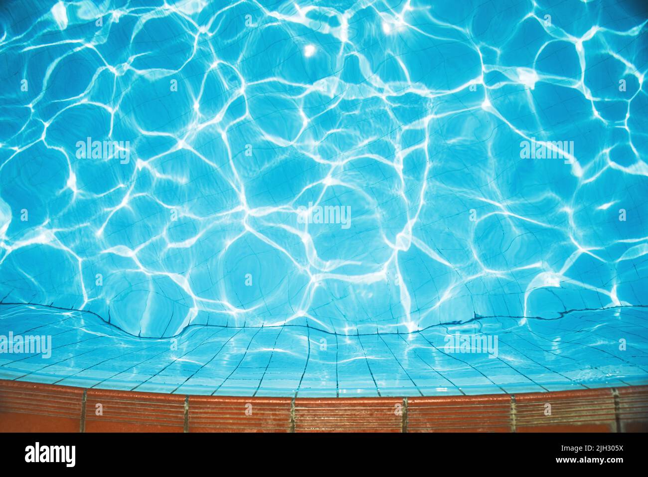 El fondo del agua, la superficie de la piscina en las ondas y el resplandor del sol. Fondo natural, concepto vacacional Piscina, gran diseño para cualquier propósito. Foto de stock