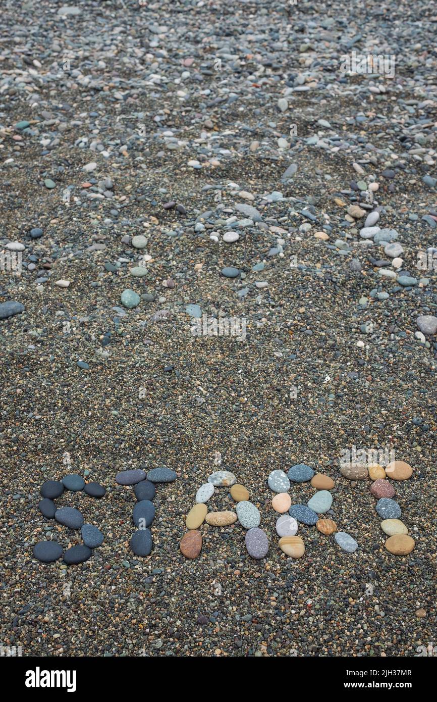 Comienzo de la palabra hecho de piedras en la playa de arena. Orientación vertical. Foto de stock