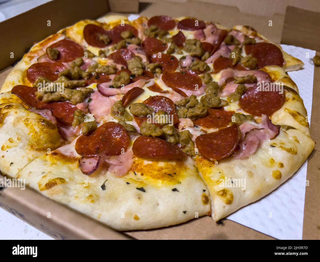 Primer plano, enfoque selectivo en una pizza amantes de la carne dentro de una caja de entrega de cartón Foto de stock