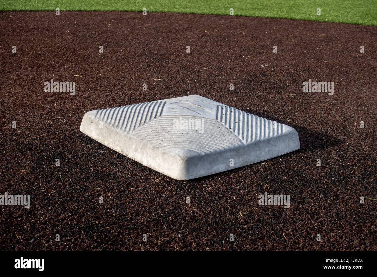 vista de cerca de una base en un campo de béisbol limpio en un día luminoso y soleado Foto de stock