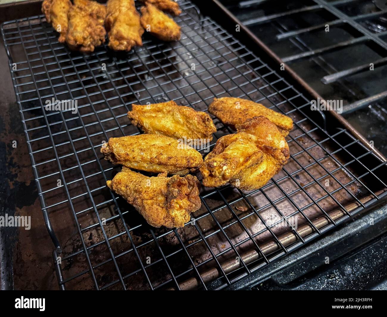 Primer plano, enfoque selectivo en alitas de pollo fritas caseras en un tendedero dentro de una cocina casera Foto de stock
