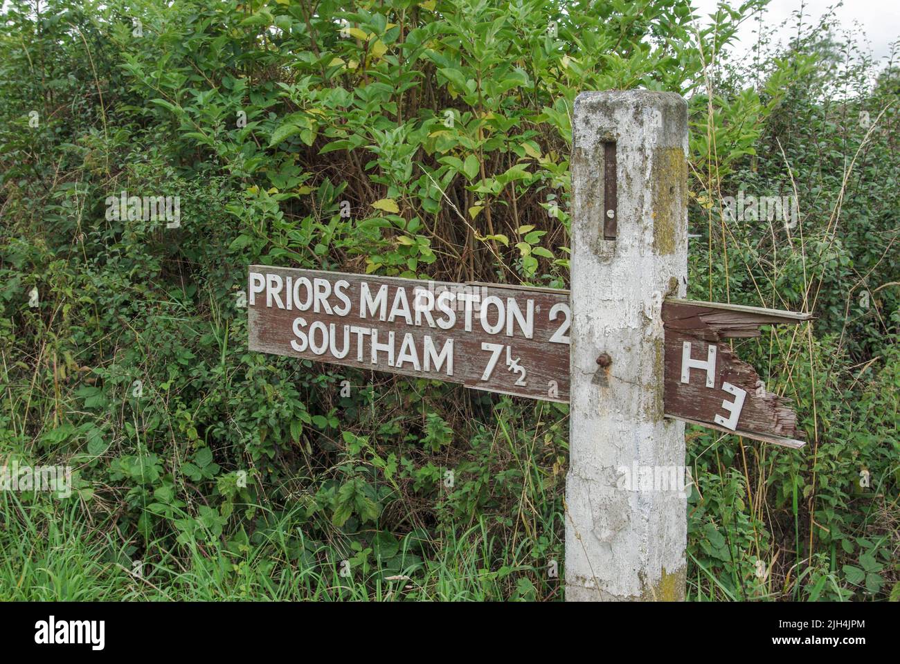 Antiguo cartel de madera, parcialmente decayado, en el pueblo de Helidon, Northamptonshire; indicando dirección a Priors Marston y Southam Foto de stock