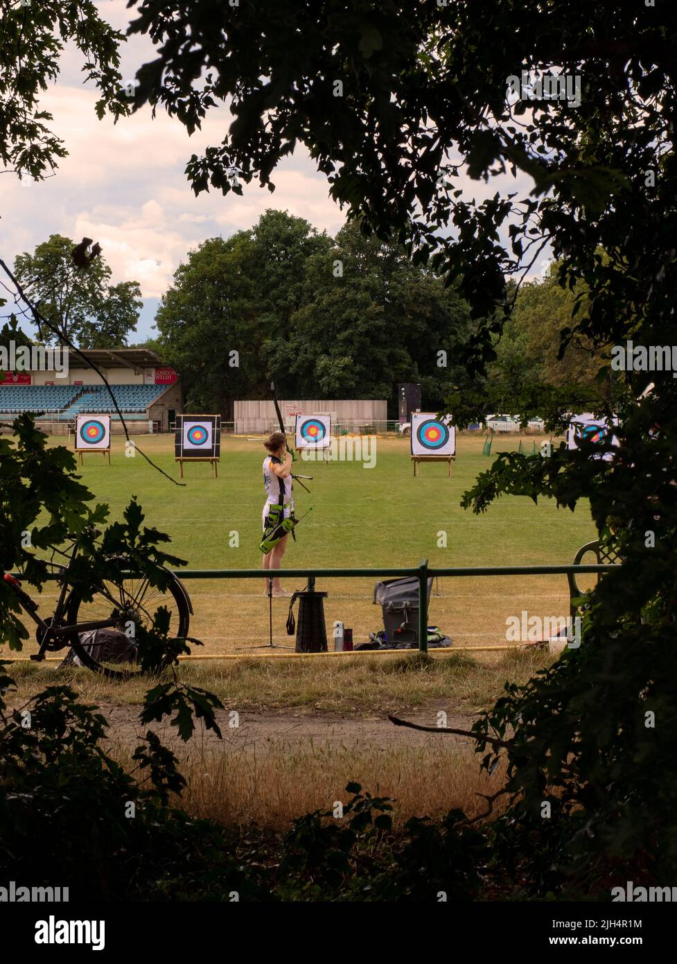 Archer haciendo prácticas de blanco en el Old Deer Park, Richmond, Surrey, Reino Unido visto a través de una pantalla de árboles Foto de stock
