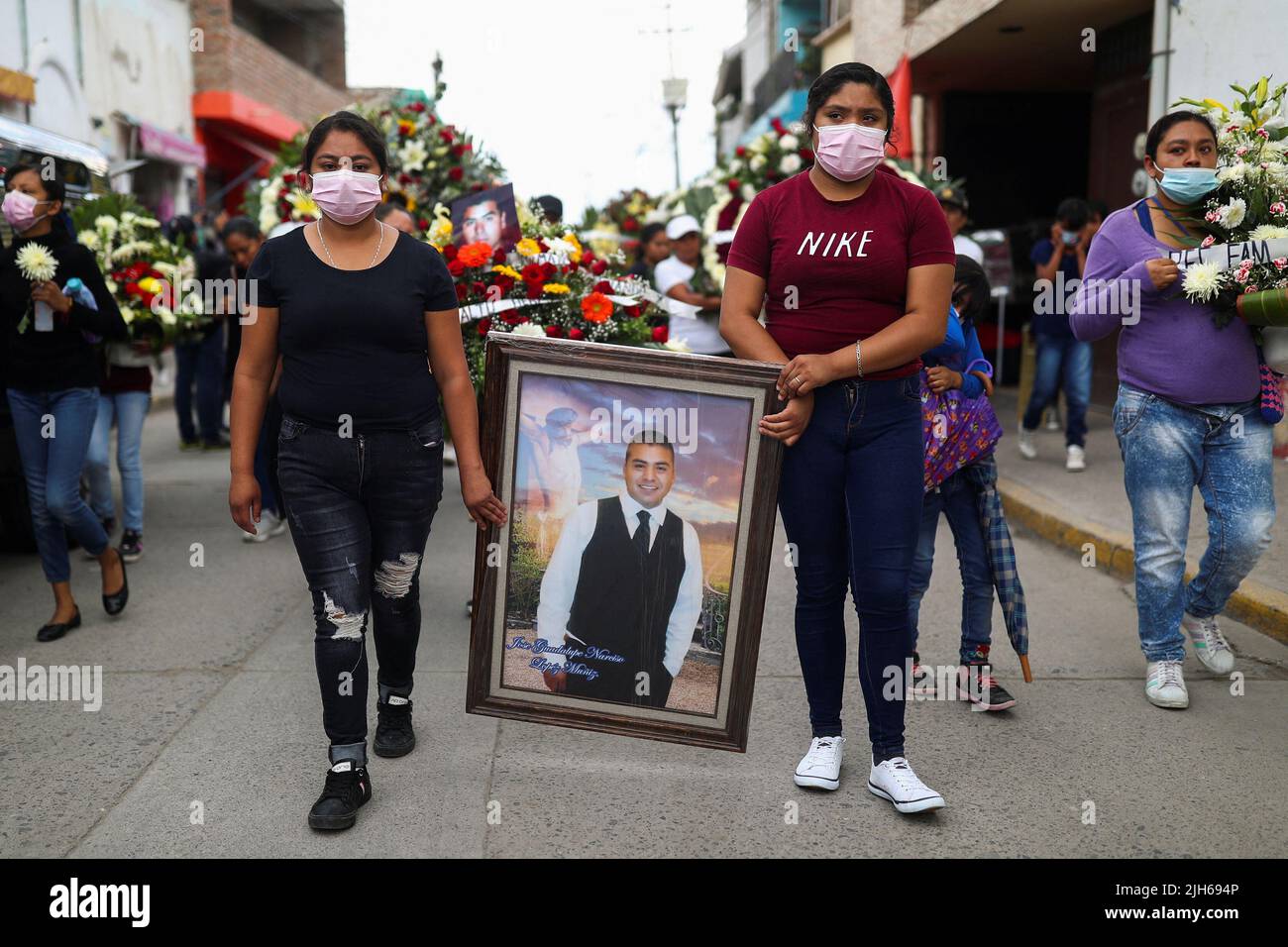 Las mujeres llevan un retrato del fallecido migrante José López, de 34 años, quien murió en un camión de remolque en Texas, mientras asistía a su funeral después de que sus restos fueran repatriados a México, en Celaya, estado de Guanajuato, México, el 15 de julio, 2022. REUTERS/Edgard Garrido Foto de stock