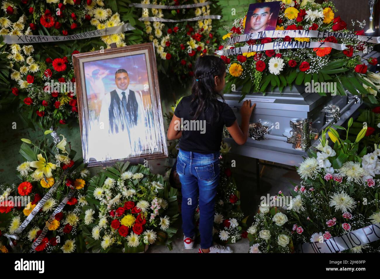 Una niña toca el ataúd del difunto migrante José López, de 34 años, quien murió en un camión de remolque en Texas, durante su funeral después de que sus restos fueran repatriados a México, en Celaya, estado de Guanajuato, México, el 15 de julio, 2022. REUTERS/Edgard Garrido Foto de stock