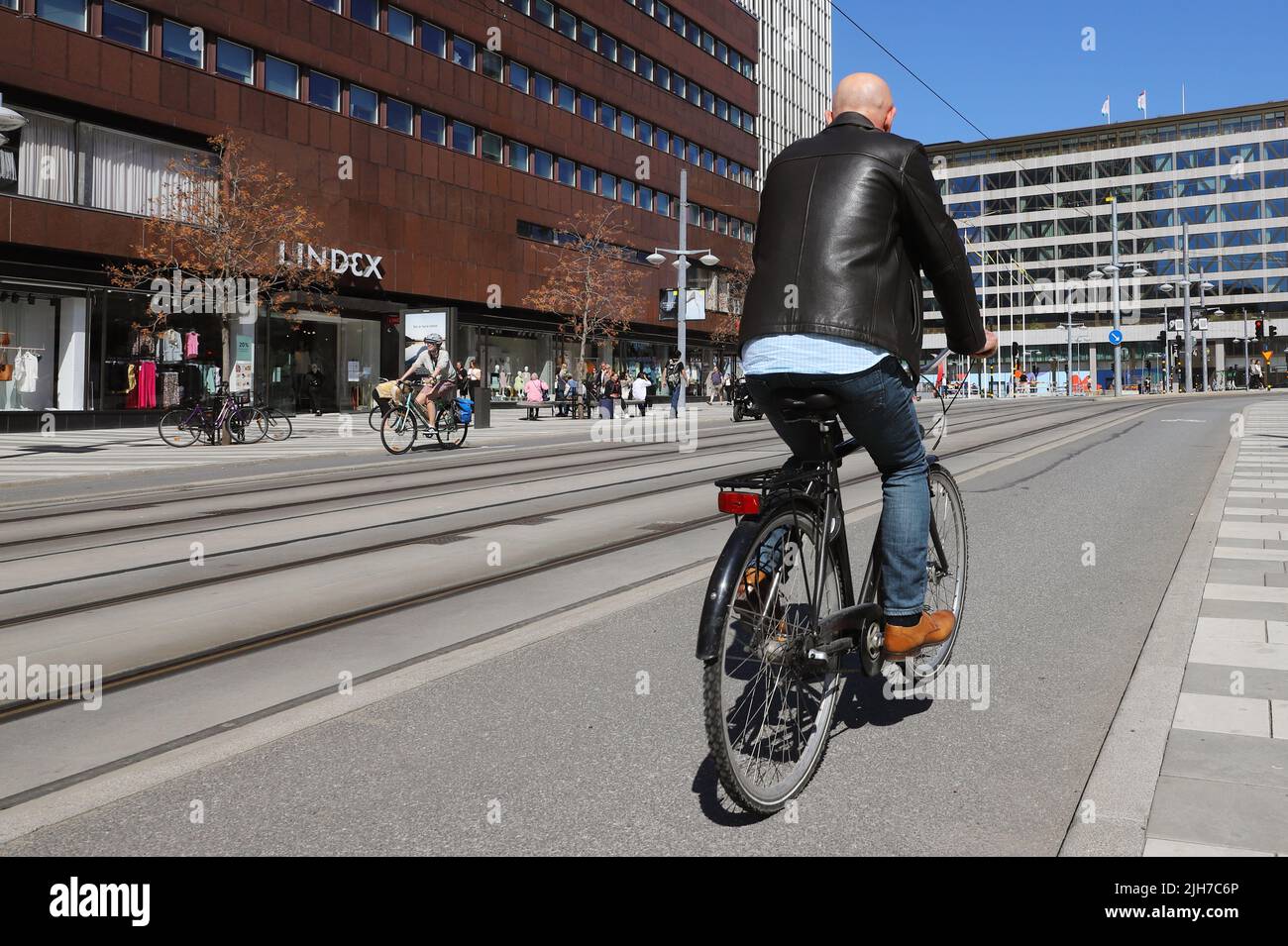 Estocolmo, Suecia - 12 de mayo de 2021: Vista trasera de un ciclista masculino recorre el carril bici de la calle Klarabergsgatan en la plaza Sergels Torg. Foto de stock