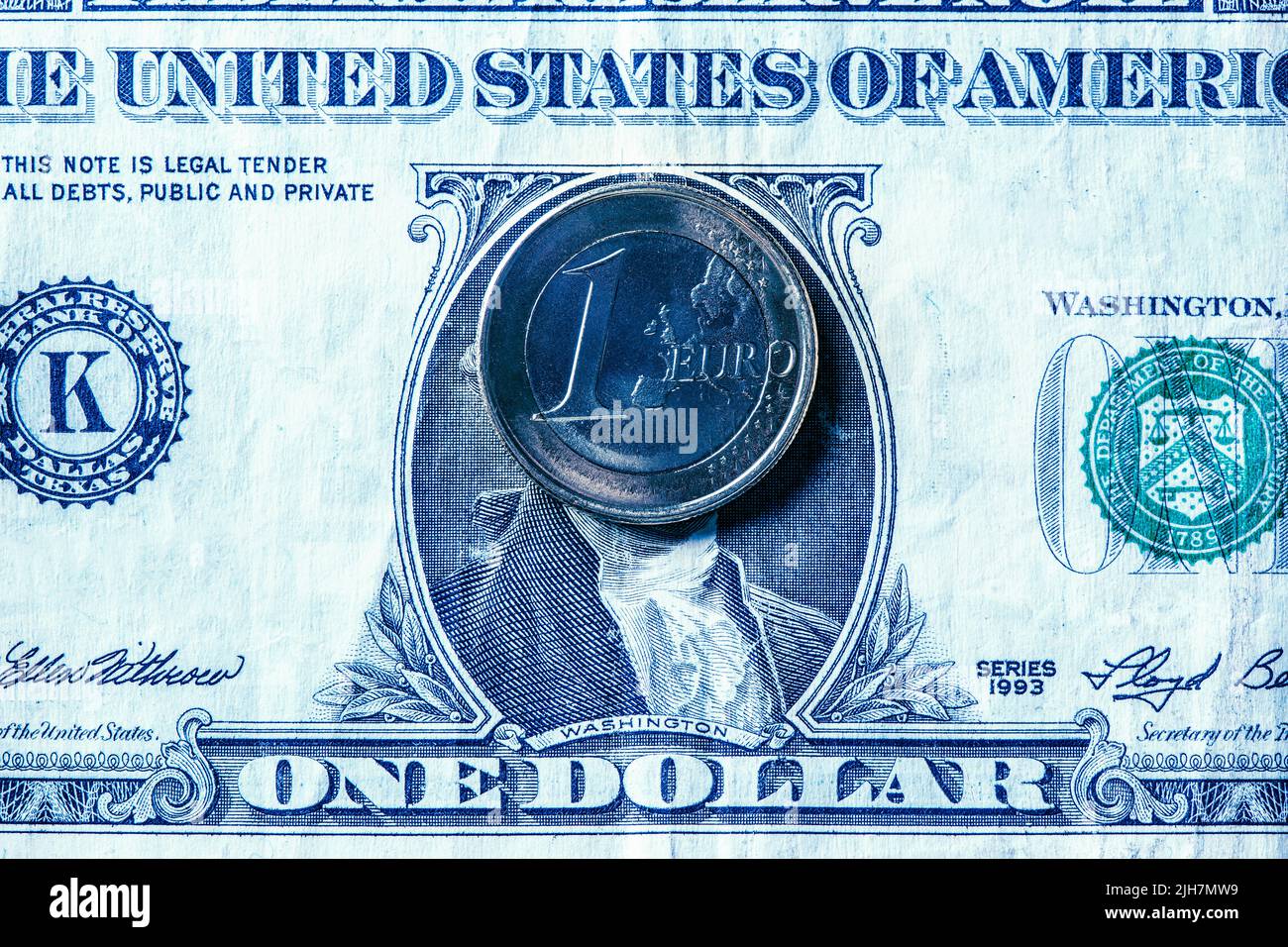 Primer plano de una moneda de un euro en un billete de un dólar estadounidense, que representa la paridad cercana entre las dos monedas Foto de stock