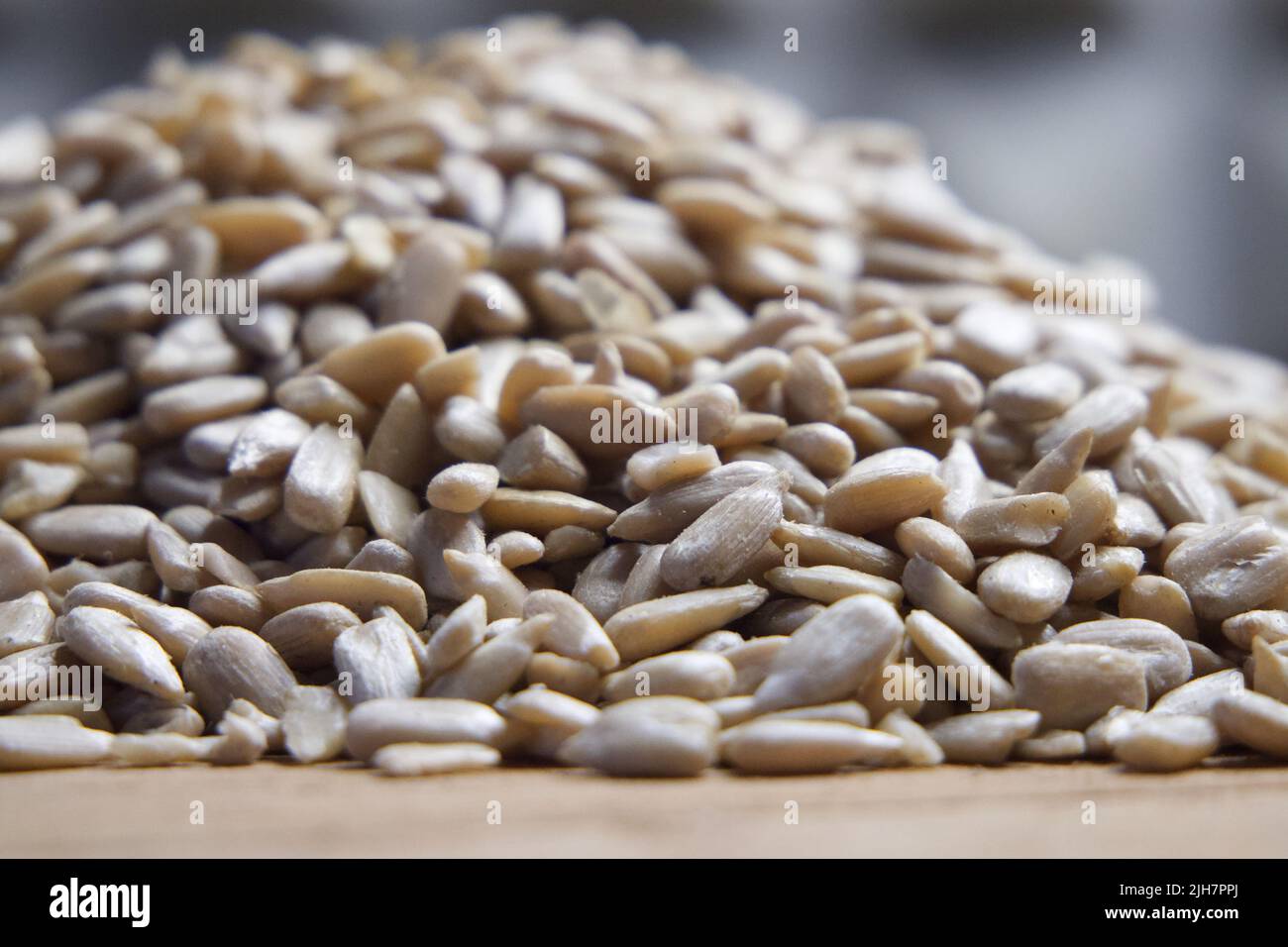 Un montón de semillas de girasol peladas sobre una superficie de madera, primer plano. Semillas de girasol sin cáscara. Foto de stock