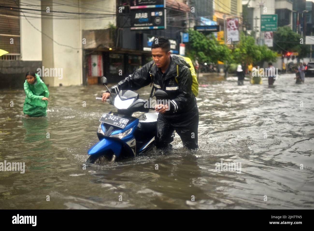 Un hombre llevando su motocicleta a través de las inundaciones en Yakarta, después de una continua lluvia dejó inundada el centro de la ciudad capital de Indonesia. Foto de stock