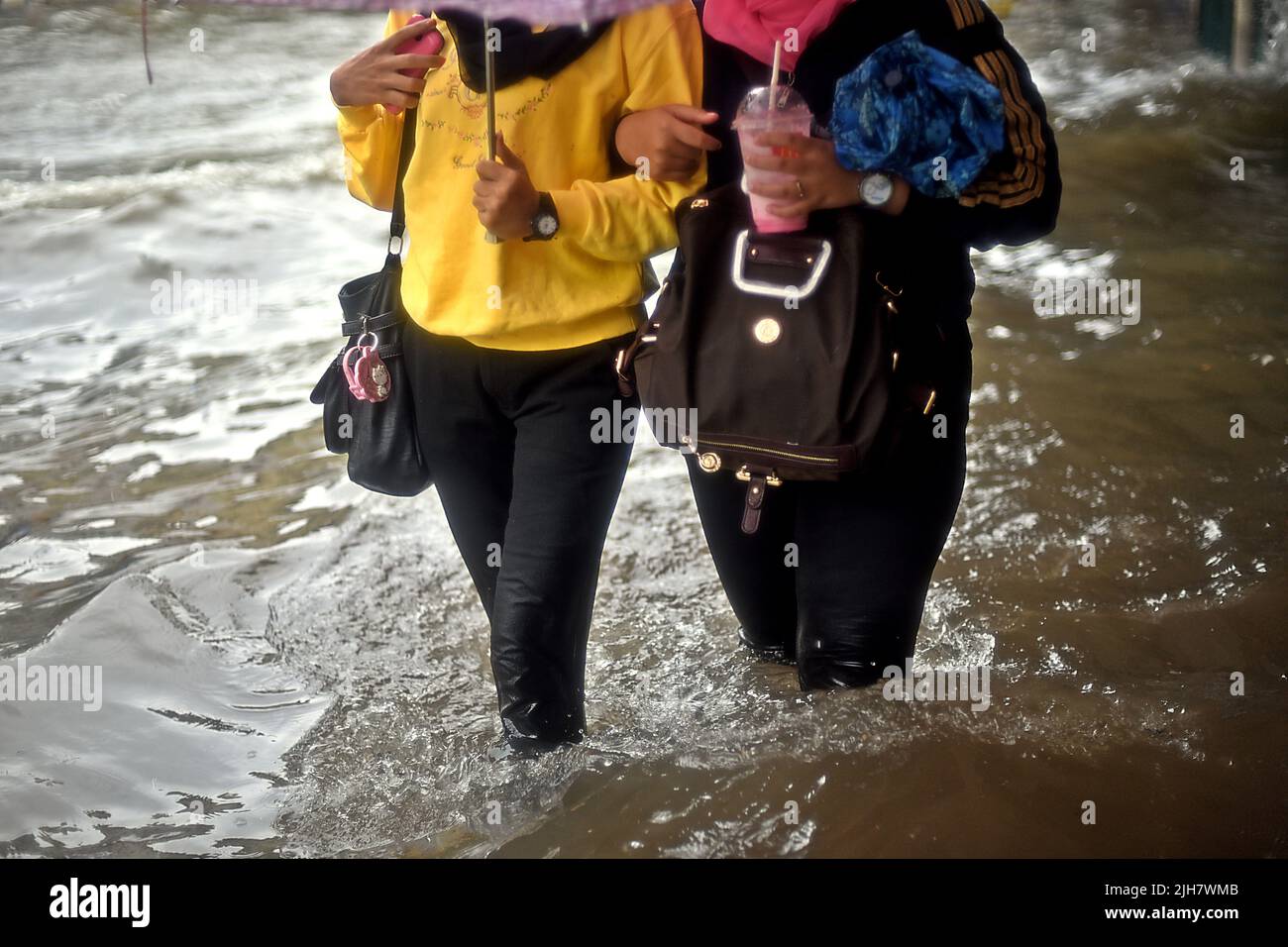 Las mujeres caminando por un camino inundado en Yakarta, después de una lluvia continua dejó inundada la zona del centro de la ciudad capital de Indonesia. Foto de stock