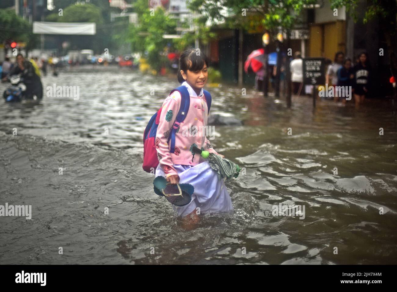 Un estudiante caminando a través de una calle inundada en el centro de Yakarta, después de una lluvia continua dejó inundada la capital de Indonesia. Foto de stock