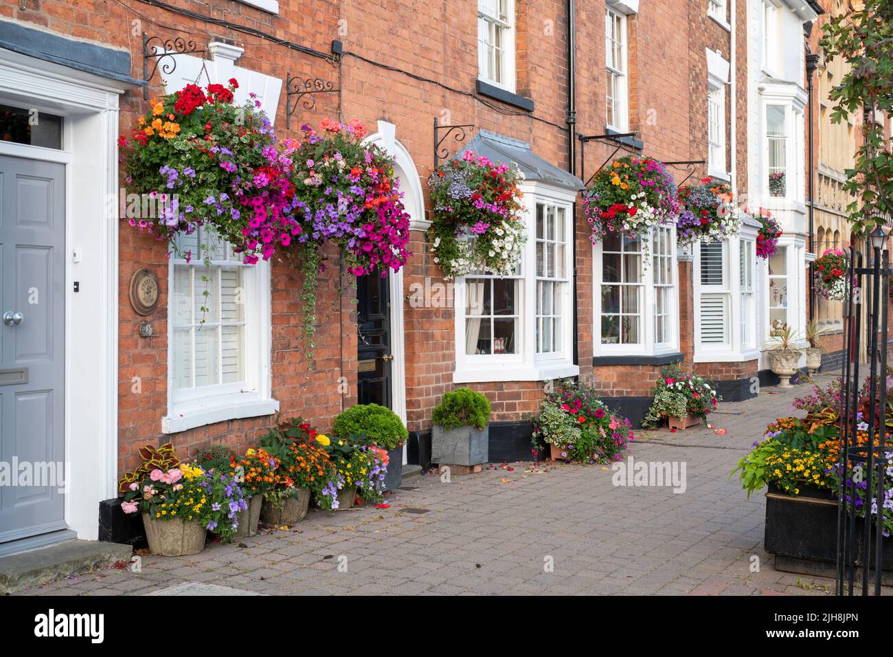 Cestas colgantes de flores en los frentes de la casa en la ciudad de Pershore, Worcestershire, Reino Unido Foto de stock