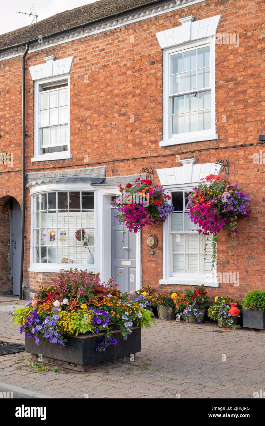 Cestas colgantes de flores en los frentes de la casa en la ciudad de Pershore, Worcestershire, Reino Unido Foto de stock