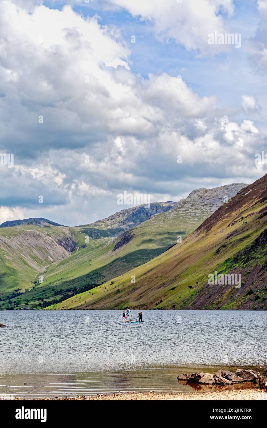 Paddleboarders en el lago de Wastwater con las pendientes espectaculares del grito en el fondo, en un día del verano Wasdale, Cumbria Inglaterra Reino Unido Foto de stock