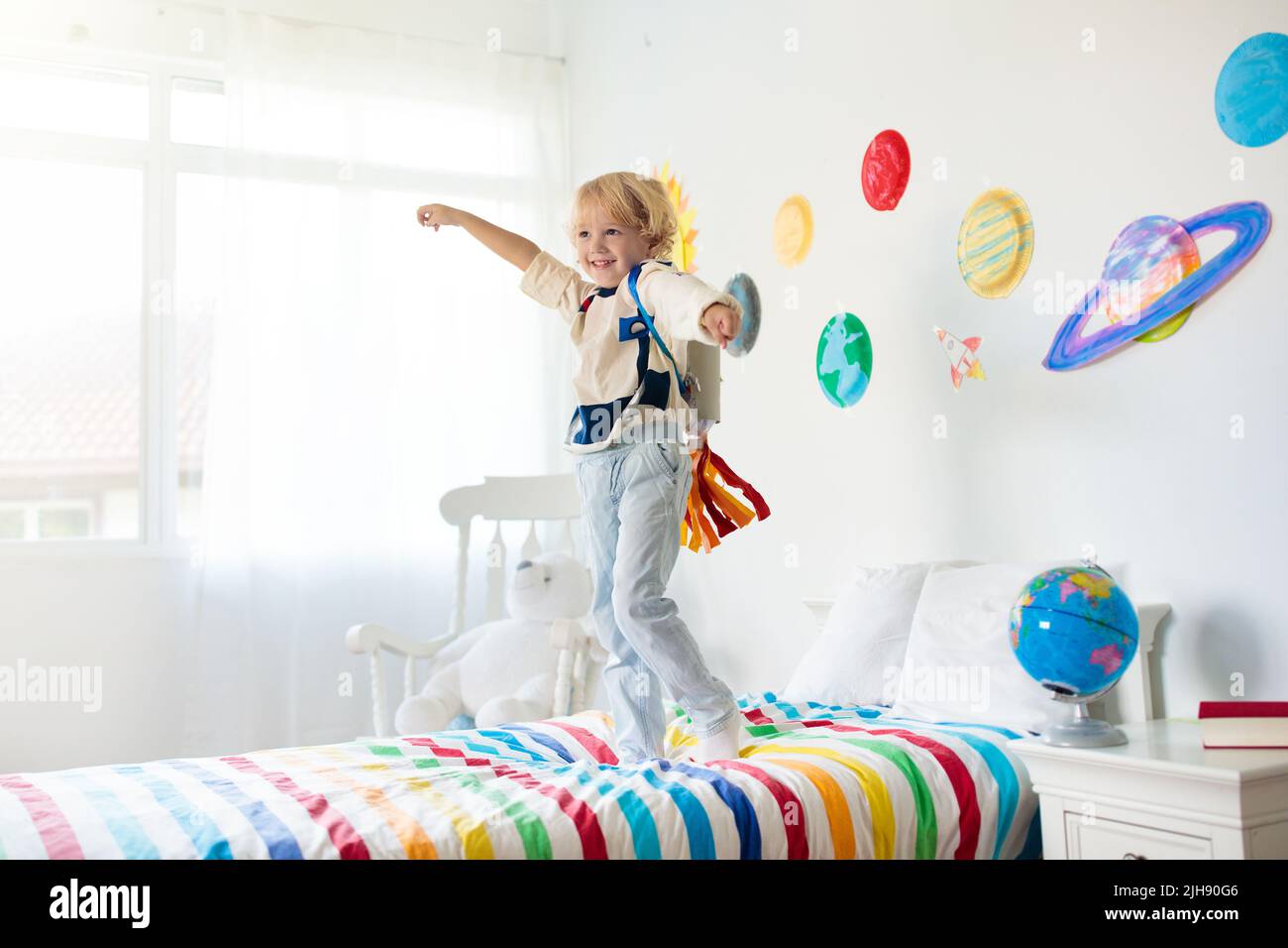 Los niños juegan a astronauta. Niño pequeño en traje espacial saltando en  la cama con cohete. Sistema solar y decoración de la sala de planeta  Fotografía de stock - Alamy