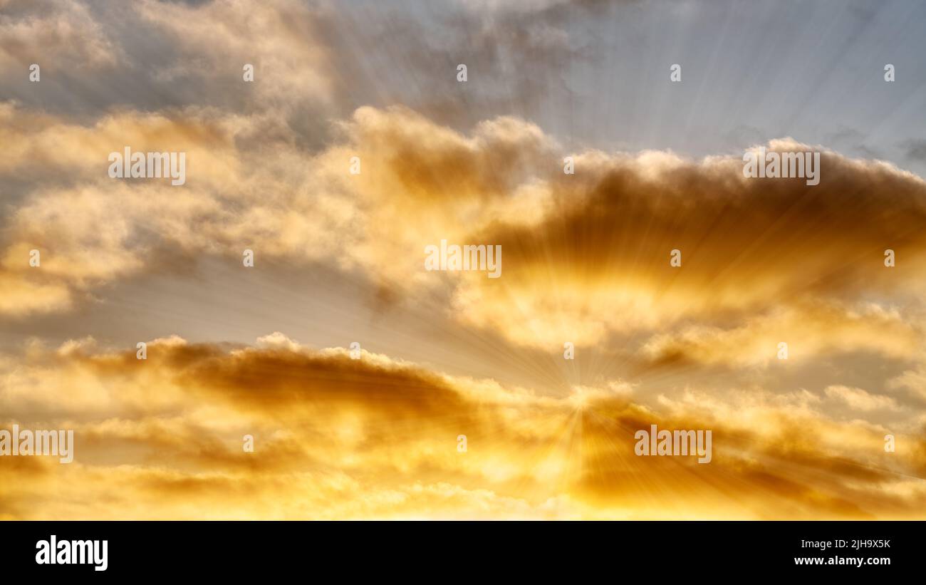 Los rayos del sol están rompiendo a través De Un Cloudscape de color dorado Foto de stock