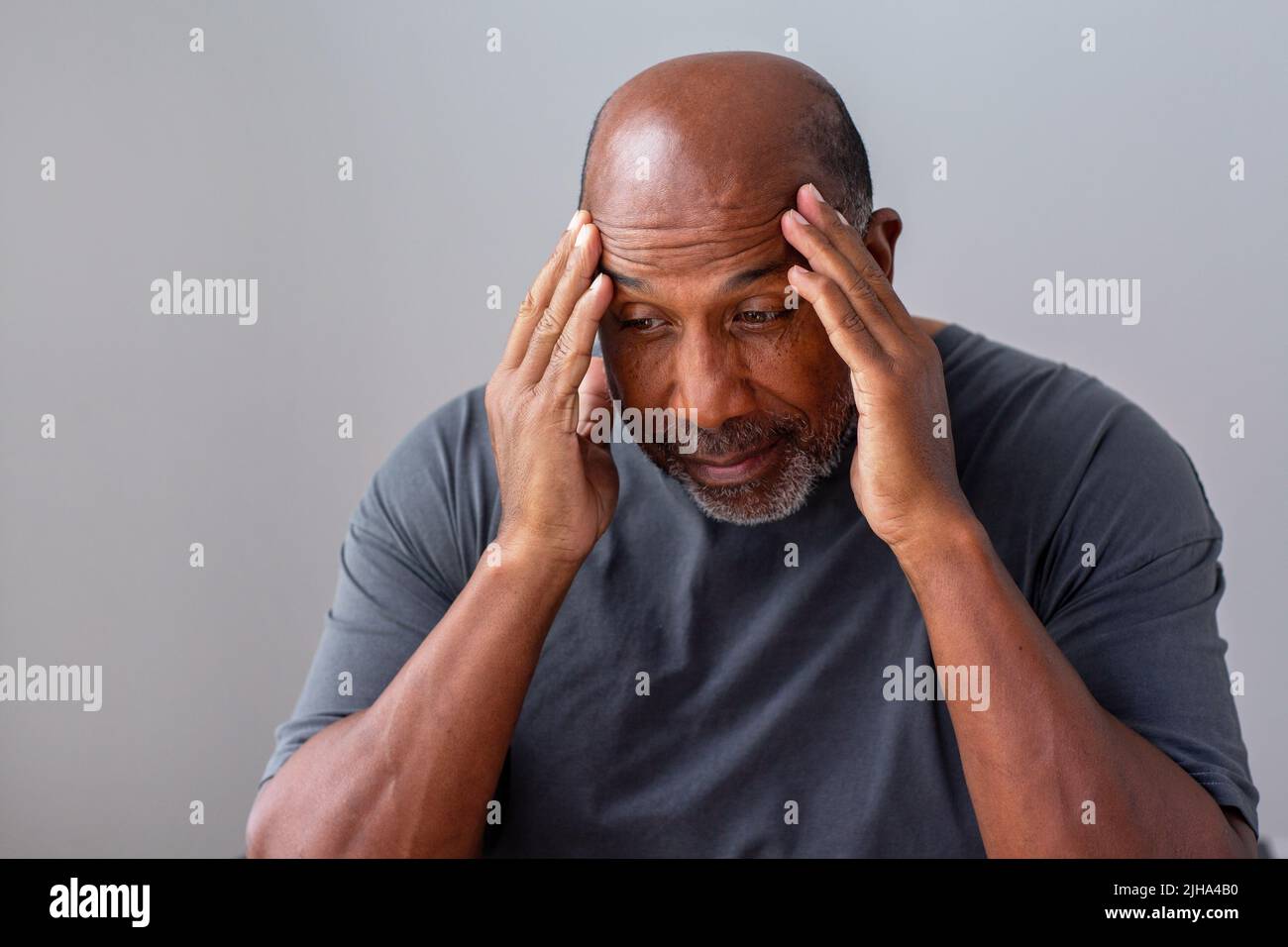 El hombre africano americano maduro no se siente bien con sus manos en su cabeza. Foto de stock