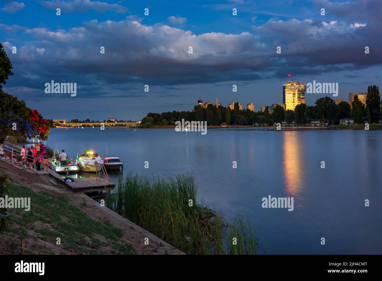 Viena: Lago oxbow Alte Donau (Danubio antiguo), puesta de sol, fiesta privada en los barcos, Torre IZD en 22. Donaustadt, Viena, Austria Foto de stock