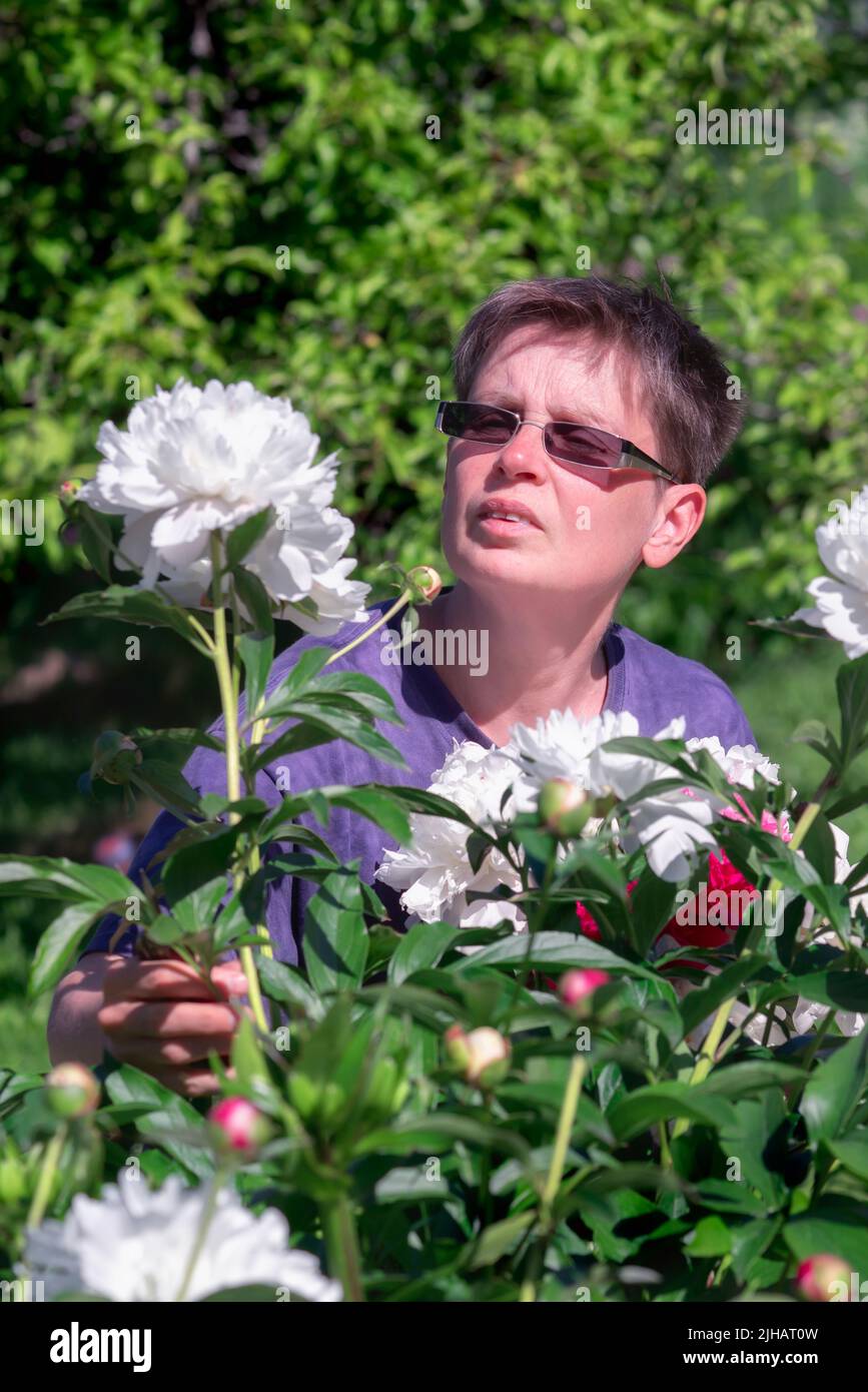 Mujer con flores de peonía en un jardín Foto de stock