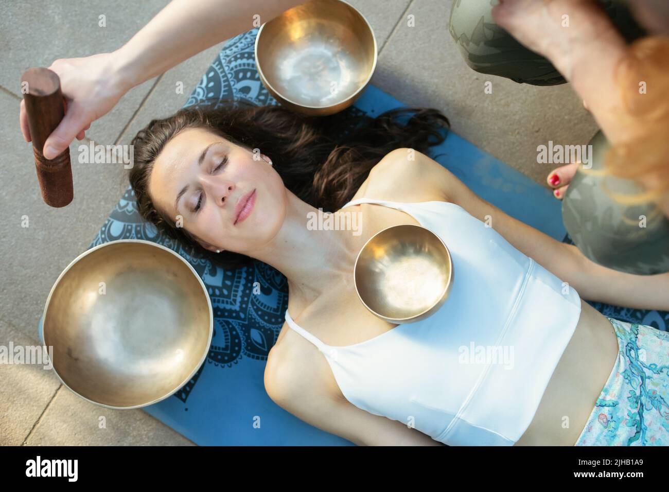 Concepto de yoga, meditación y terapia de sonido. Hermosa joven caucásica rodeada de cuencos y instrumentos de canto tibetano de cobre. Foto de stock