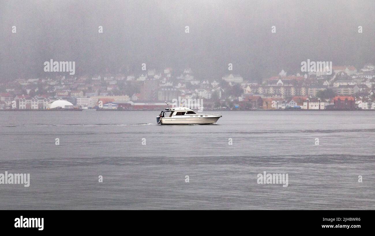 Embarcaciones de recreo, junio llegando a Byfjorden, fuera del puerto de Bergen, Noruega. Sandviken visible a través de la niebla y la lluvia Foto de stock