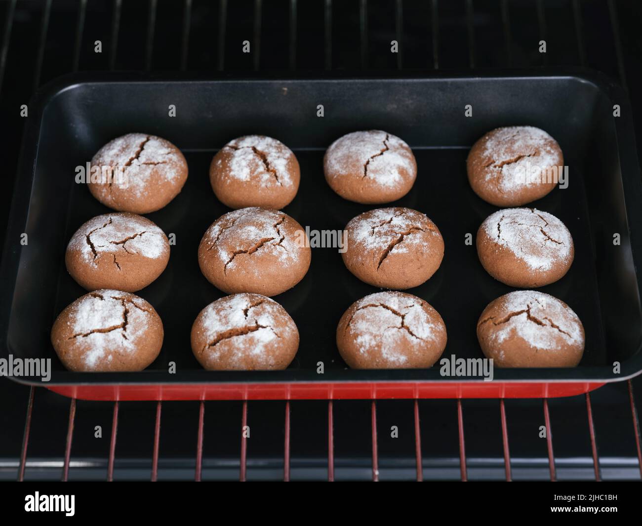 Una bandeja para hornear con doce galletas caseras en un horno. Foto de stock