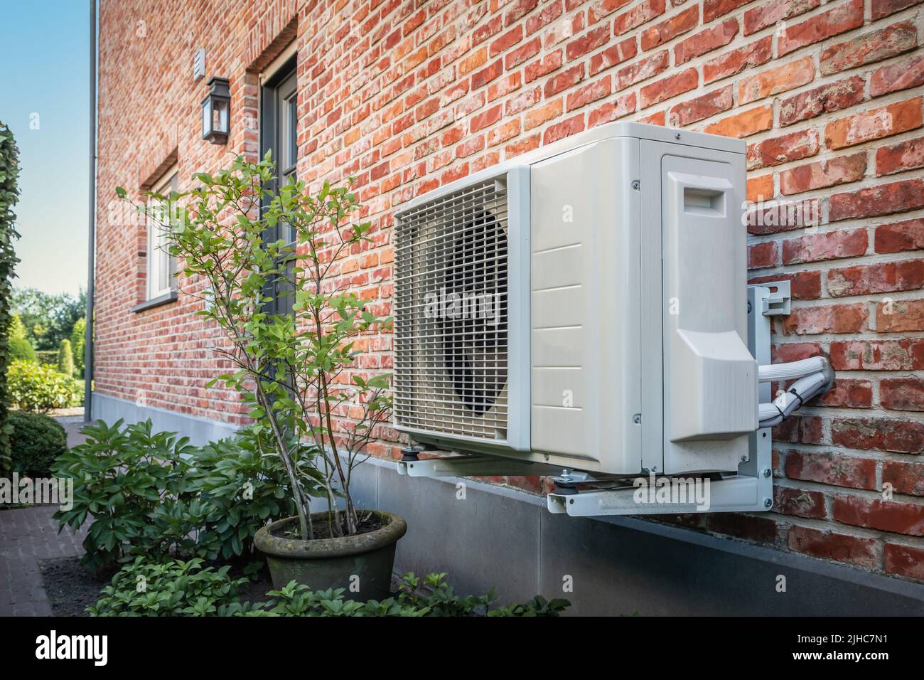 Bomba de calor aire a aire para enfriar o calentar la casa. Unidad exterior alimentada por energía renovable. Foto de stock